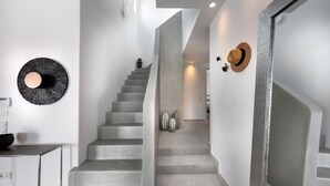 Uma escadaria moderna com design minimalista, uma peça de arte circular na parede e alguns objetos decorativos.