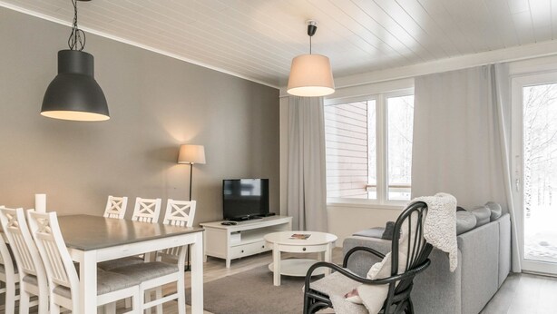 A modern living room with a dining area, a sofa, a TV, and a fireplace. - Skivillas paljakka 1. (3mh) by Interhome (Puolanka)