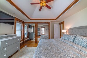 Un dormitorio con una cama grande, un ventilador de techo y techo de madera.