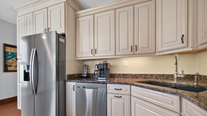 A kitchen with stainless steel appliances, white cabinetry, a granite countertop, and a built-in dishwasher. - Fins Up home- Park Views, Close to Beach, Shops (Cape Charles)