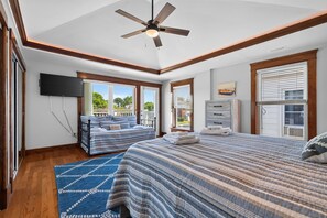 A bedroom with a bed, a TV, a ceiling fan, and a window with blinds.