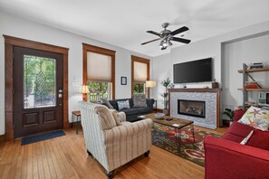 A living room with a fireplace, a television, and a ceiling fan. - Fins Up home- Park Views, Close to Beach, Shops (Cape Charles)