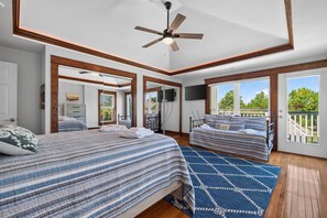 A bedroom with two beds, a ceiling fan, a TV, and a view of the outdoors. - Fins Up home- Park Views, Close to Beach, Shops (Cape Charles)