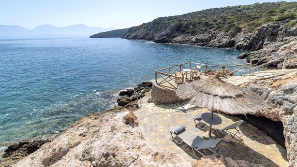 A coastal terrace with a thatched umbrella, lounge chairs, and a stone deck overlooking the sea. - Beautiful 3-bed Sea Front Villa in Agios Nikolaos (Agios Nikolaos)