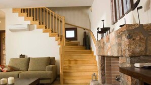 A living room with a wooden staircase, a stone fireplace, a sofa, and a coffee table. - Beautiful 3-bed Sea Front Villa in Agios Nikolaos (Agios Nikolaos)