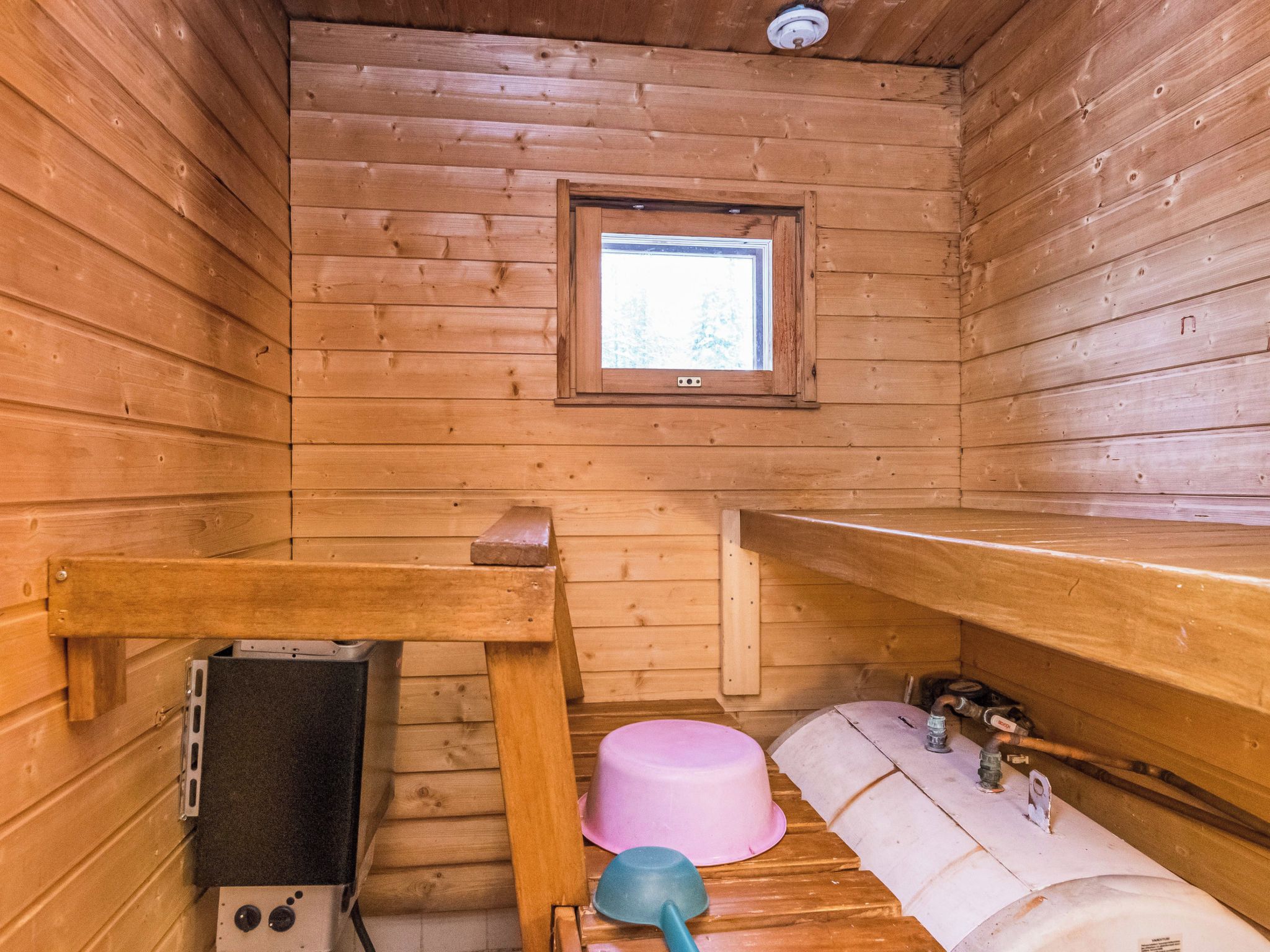 Et interiør af en træhytte med et vindue, en vask og et toilet.