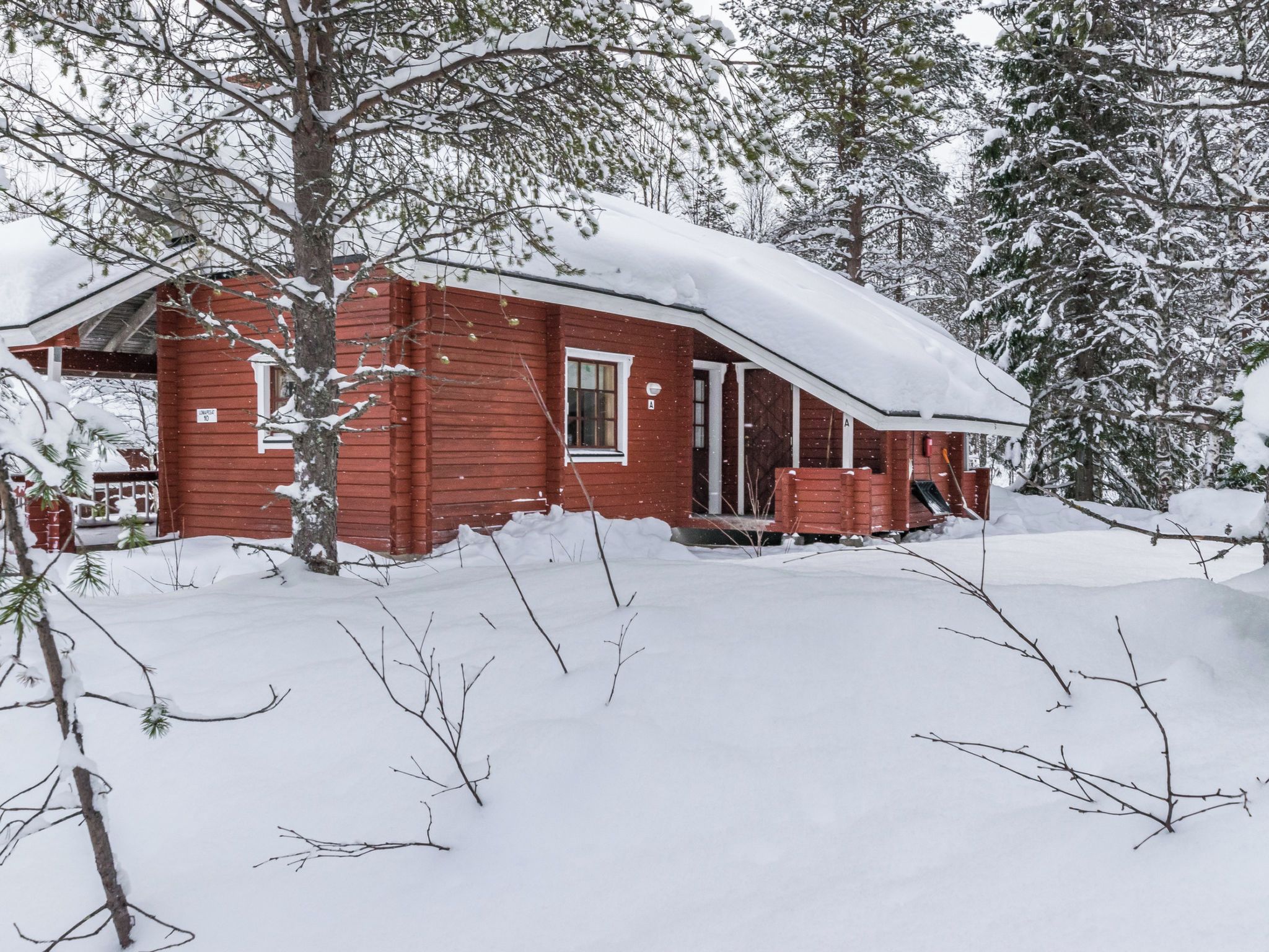 Une cabane rouge entourée d’arbres couverts de neige.