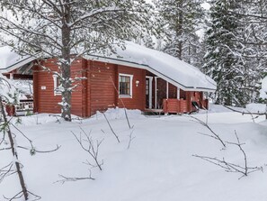 Una cabaña roja rodeada de árboles cubiertos de nieve.