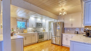 Una cocina moderna con armarios blancos, electrodomésticos de acero inoxidable y piso de madera.