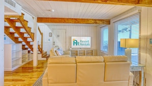Una sala de estar con sofá, una escalera y un cartel que dice 'Resort Rentals'.