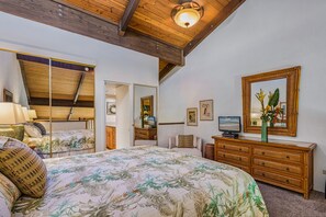 A bedroom with a bed, dresser, mirror, and ceiling fan.