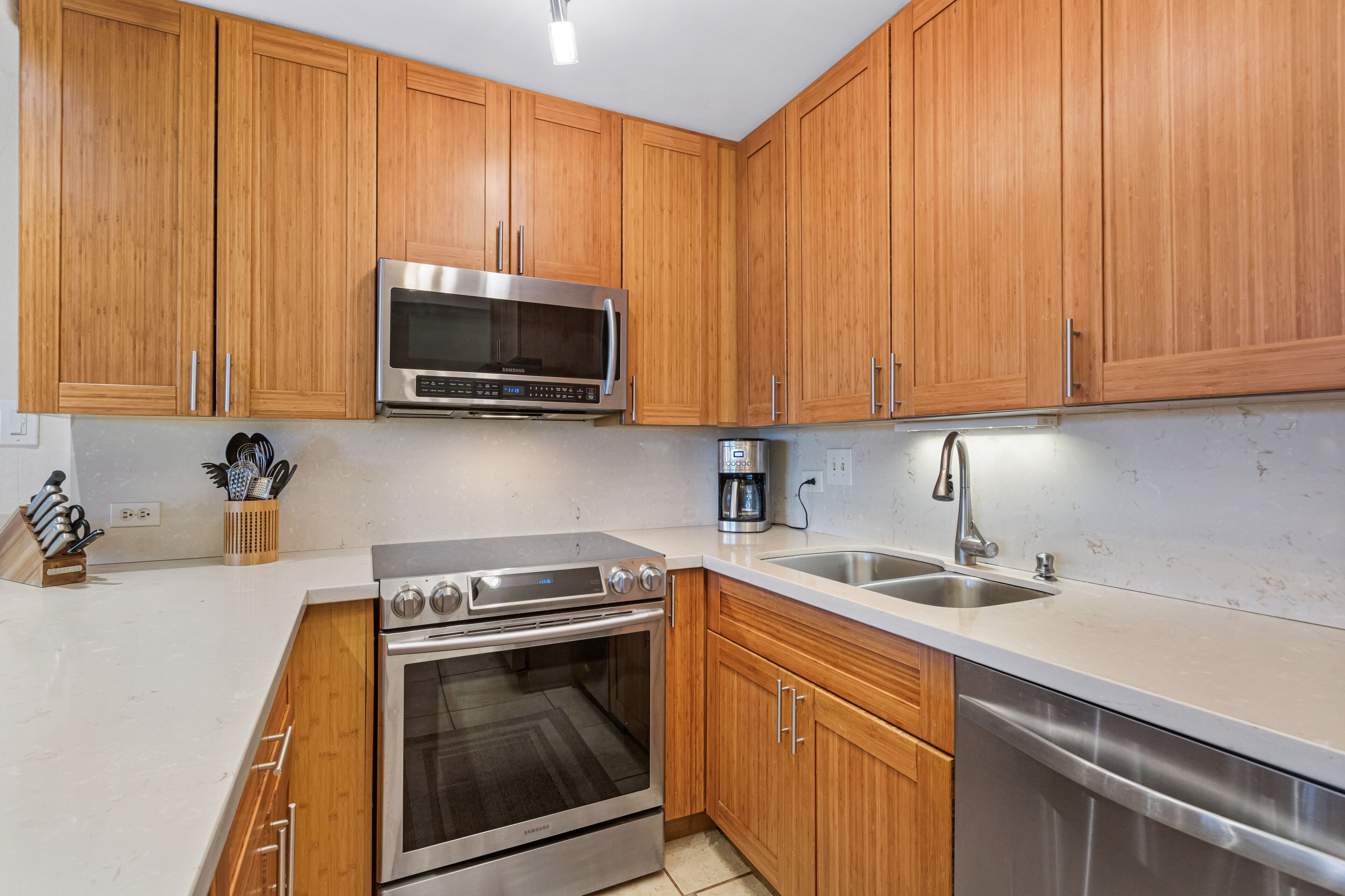 A modern kitchen with wooden cabinets, stainless steel appliances, and a white countertop.