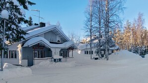 A snow-covered house with a large driveway and a garage.