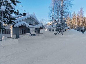 Una casa cubierta de nieve con un porche grande y un garaje.