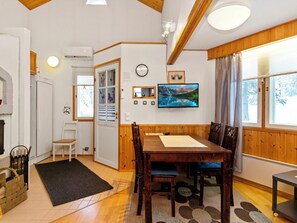 Ein Essbereich mit einem Holztisch und Stühlen, einem schwarzen Teppich und einem Fenster mit Vorhängen.