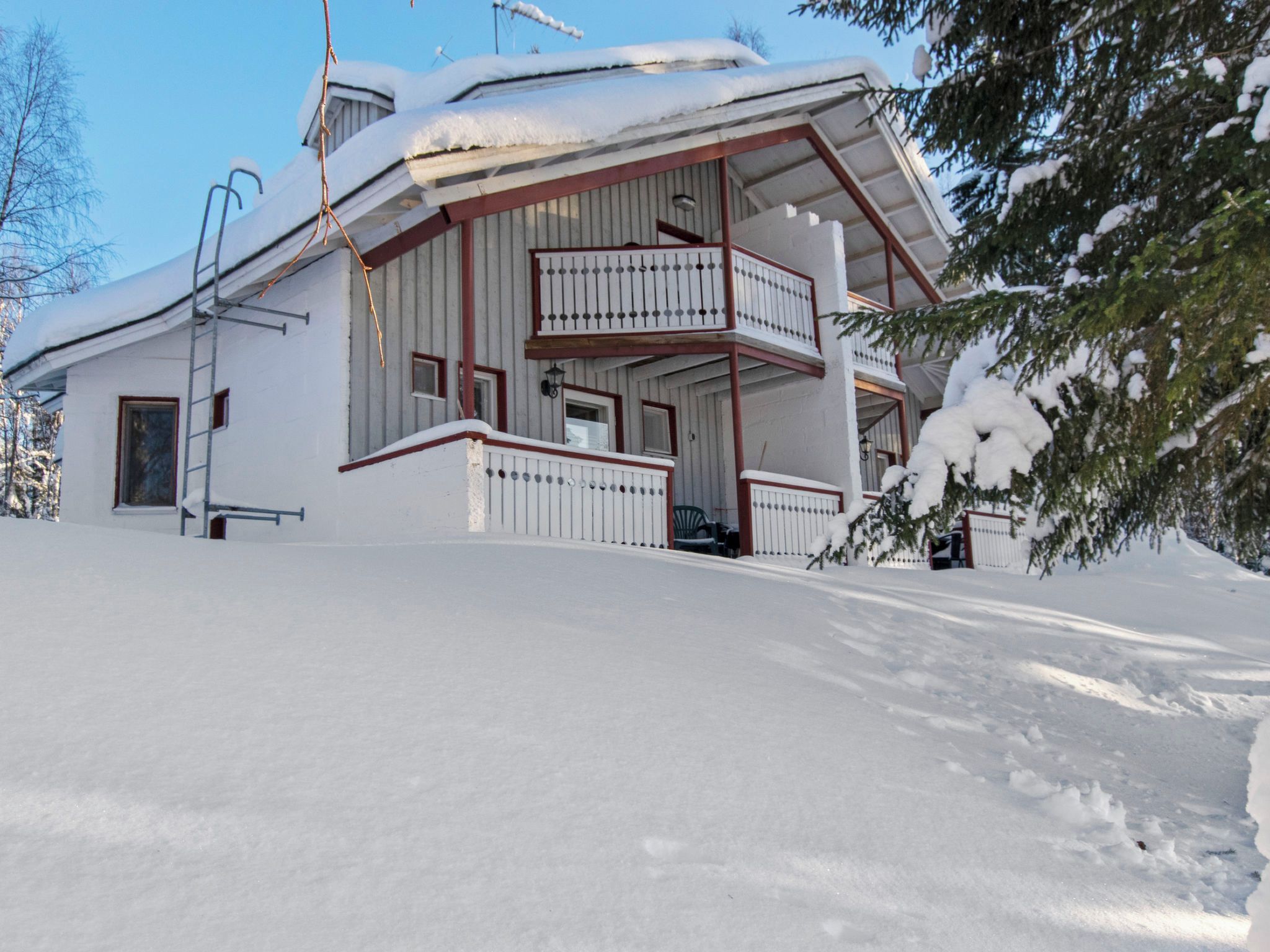 Un edificio de dos pisos con un balcón en el segundo nivel, rodeado de nieve.