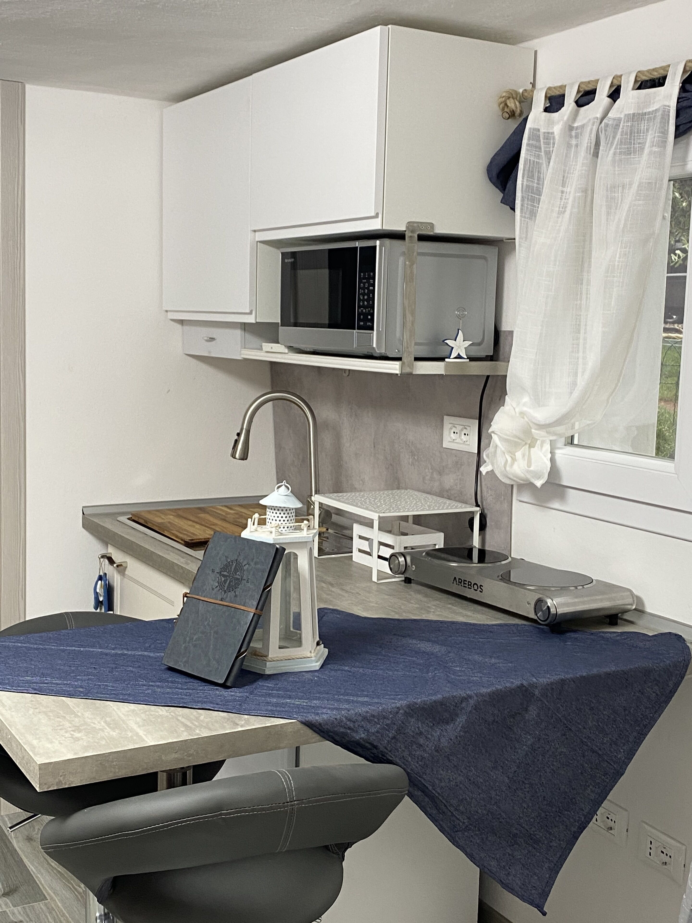 Een kleine keuken met een magnetron, een tafeltje en een stoel.