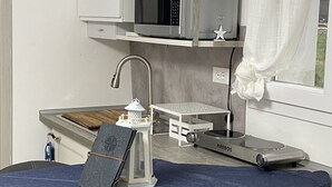 A compact kitchenette with a microwave, a small table, and a chair. - Dormire in Barca ma Sulla Terra Ferma (Campiglia Marittima)