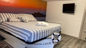 A bedroom with a bed, striped bedding, a welcome sign, a life preserver, and a TV on the wall. - Dormire in Barca ma Sulla Terra Ferma (Campiglia Marittima)