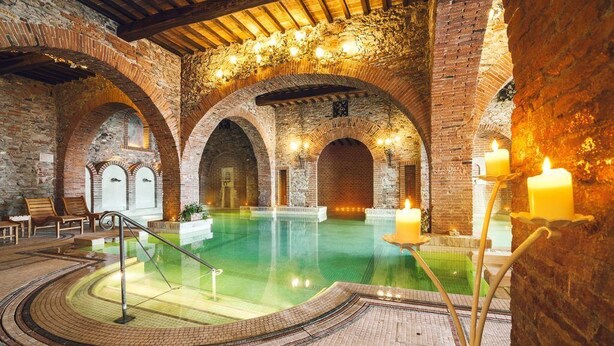 An indoor swimming pool with brick arches, a stone wall, and a wooden ceiling. - Dormire in Barca ma Sulla Terra Ferma (Campiglia Marittima)