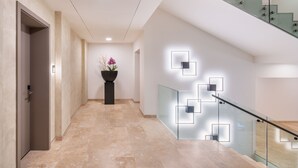 Ein moderner Flur mit Glastrennwand, einem Blumentopf und einer geometrischen Leuchte.