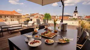 Ein Dachrestaurant mit einem gedecktem Tisch, Außenplätzen und Blick auf die Stadt.