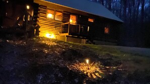 Una baita con veranda, un braciere e un piccolo spazio esterno con una luce.