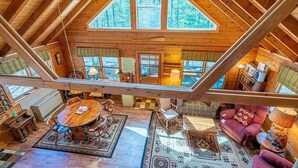 Un'ampia stanza in stile loft con soffitto alto, grandi finestre, un tavolo da pranzo in legno e un'accogliente area salotto.