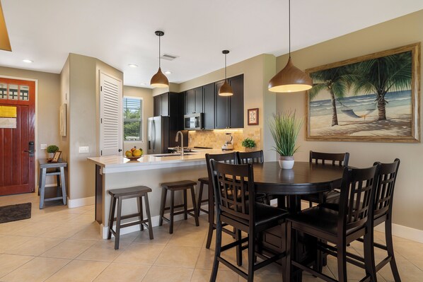 A modern kitchen with dark cabinets, a central island, and pendant lighting.