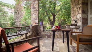A stone-floored balcony with a view of a lush green landscape, a table with a laptop, and two chairs. - Kitries Home (West Mani)