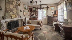 A traditional room with a stone fireplace, a dining table, and vintage furniture. - Kitries Home (West Mani)