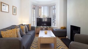 A modern living room with a grey sofa, a wooden coffee table, and a flat-screen TV.