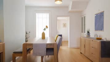 Een moderne keuken met houten kastjes, een eettafel met stoelen en een hanglamp.