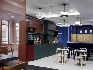 Ein modernes Café-Interieur mit Kaffeemaschine, Sitzgelegenheiten und Pendelleuchten.
