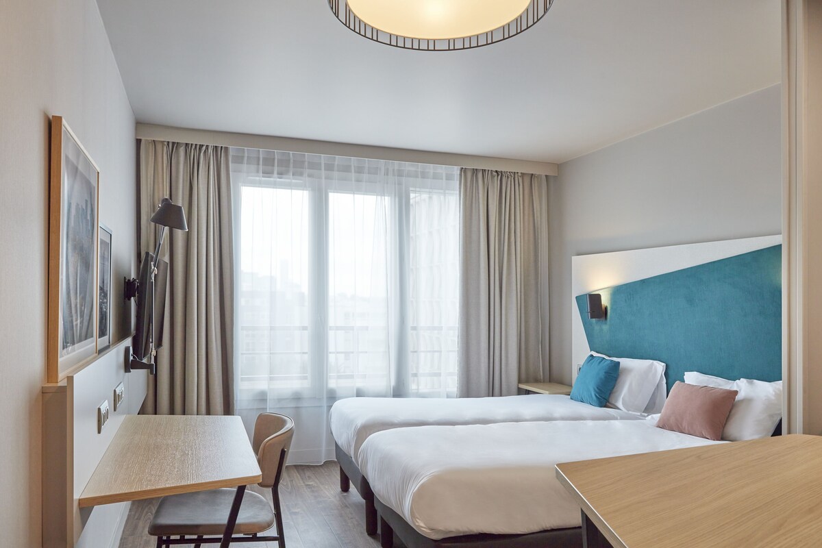 Una habitación de hotel con dos camas, un escritorio y una silla.