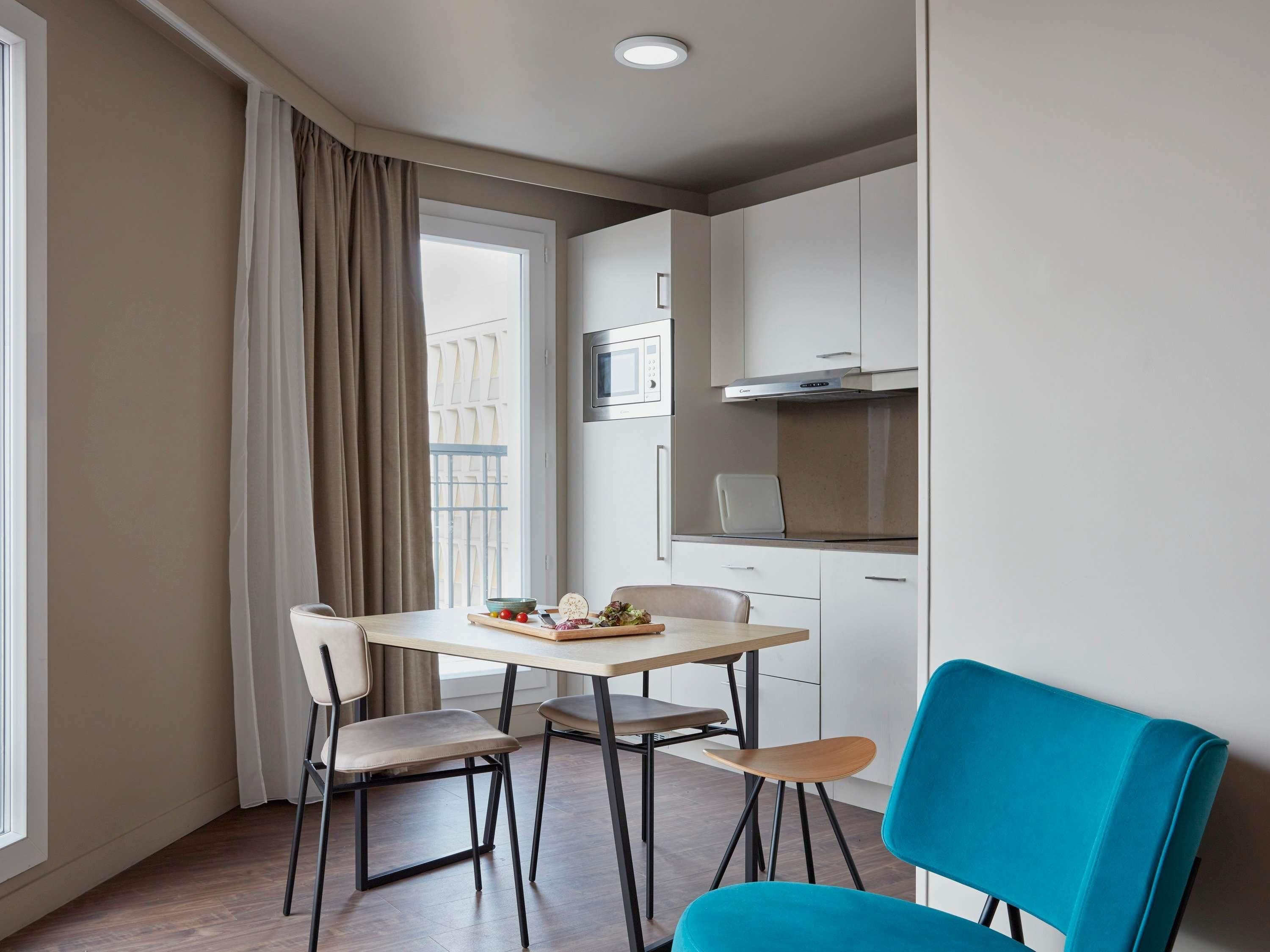 Kompakti keittiö, jossa on ruokailutila, mikroaaltouuni ja liesi.