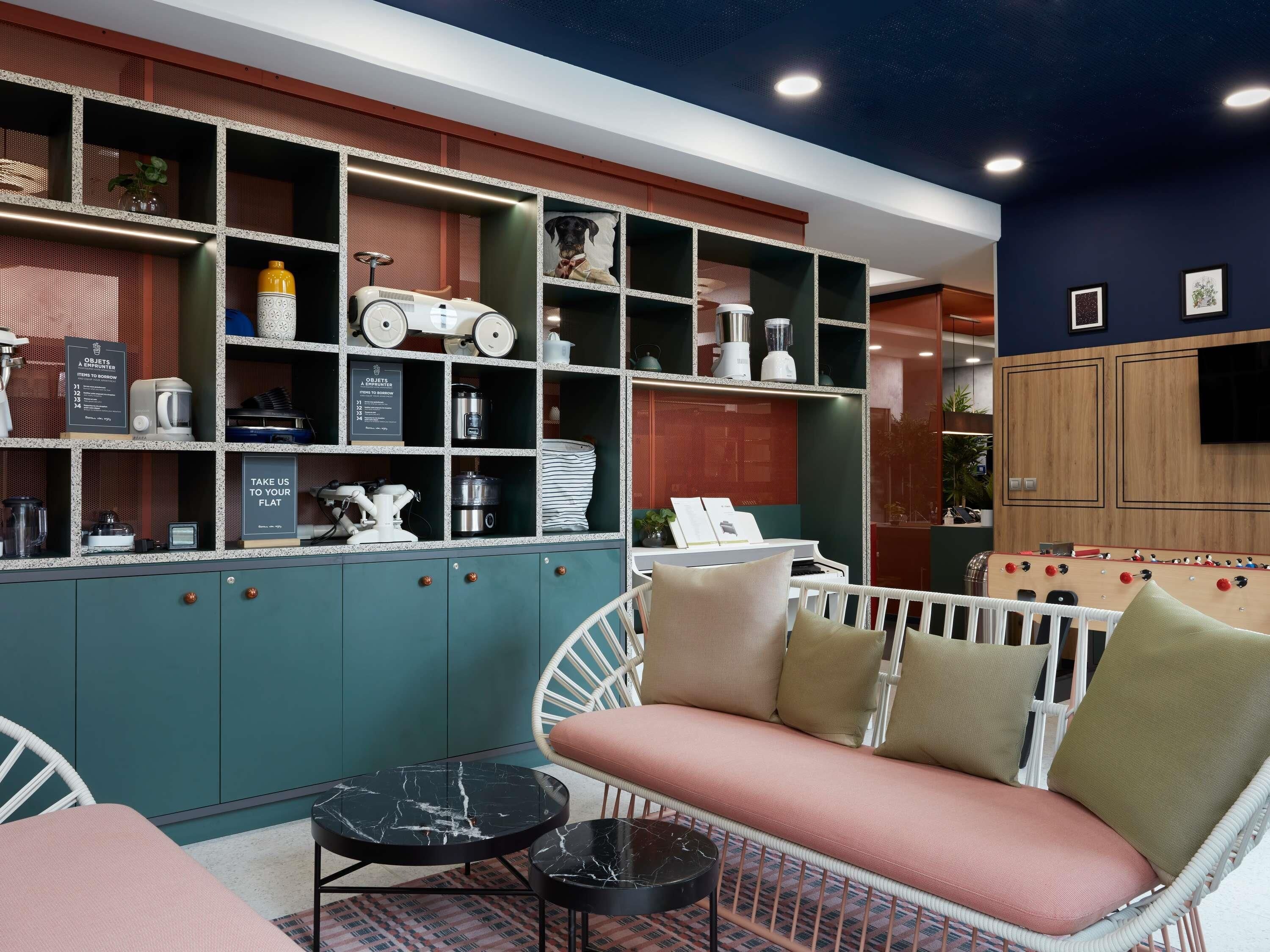 A modern living room with a sofa, two round tables, and a built-in shelving unit with various items.