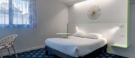 A modern bedroom with a bed, a chair, a small table, and a decorative wall piece.