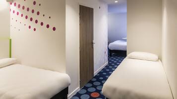 A hotel room with two beds, a door, and a hallway with a polka dot carpet.