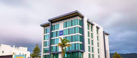 A modern hotel building with multiple floors, large windows, and a sign reading "SEBEL".