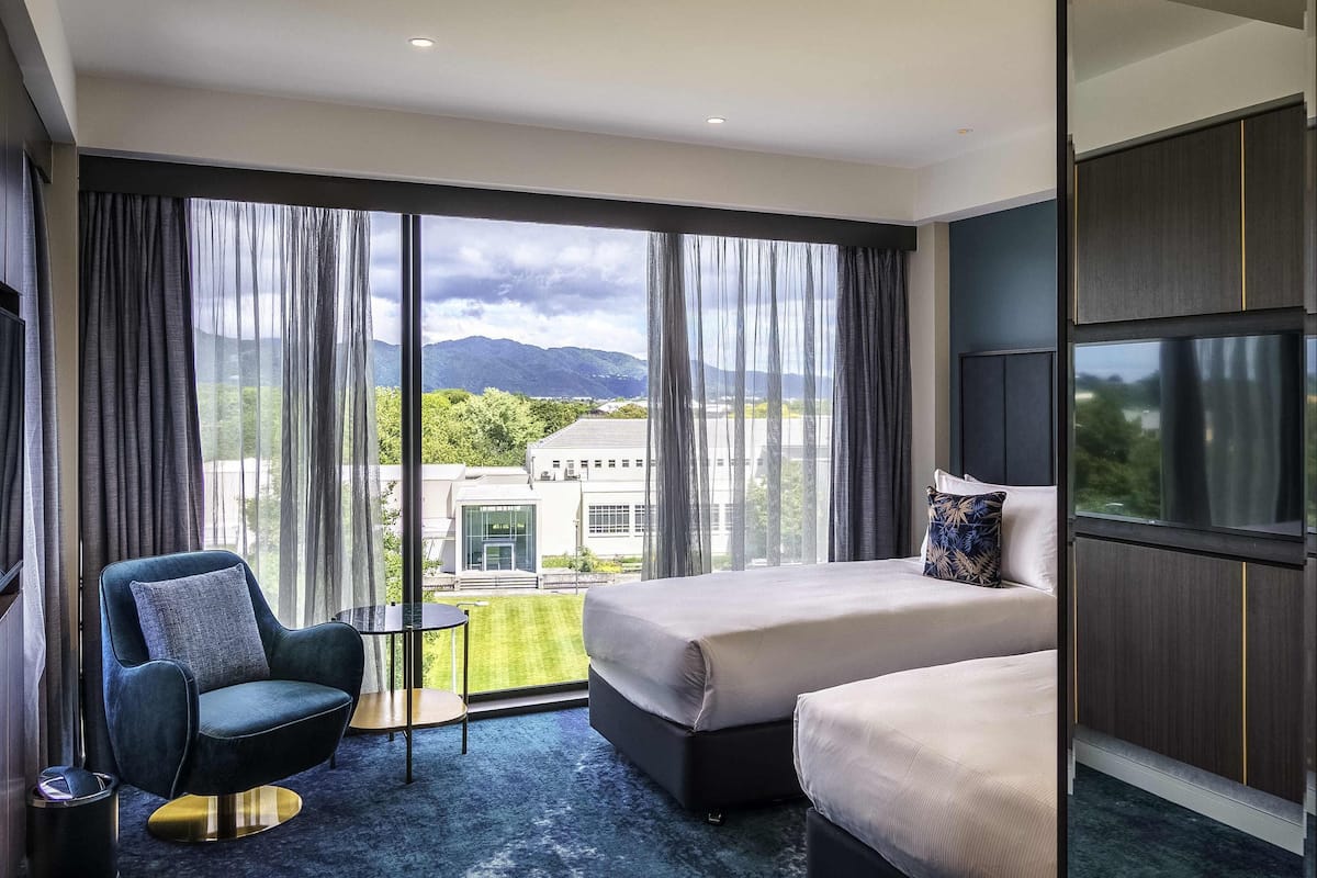 Una habitación de hotel con una cama, una silla, una mesita y un televisor.