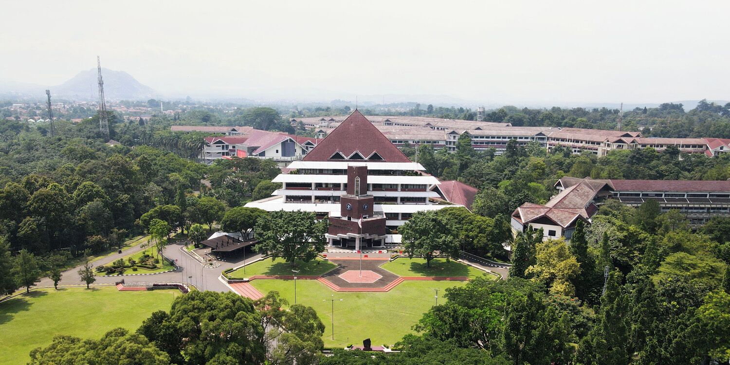 A large building with a central courtyard, surrounded by greenery and other buildings.