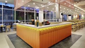 A restaurant with a central counter, seating area, and large windows.