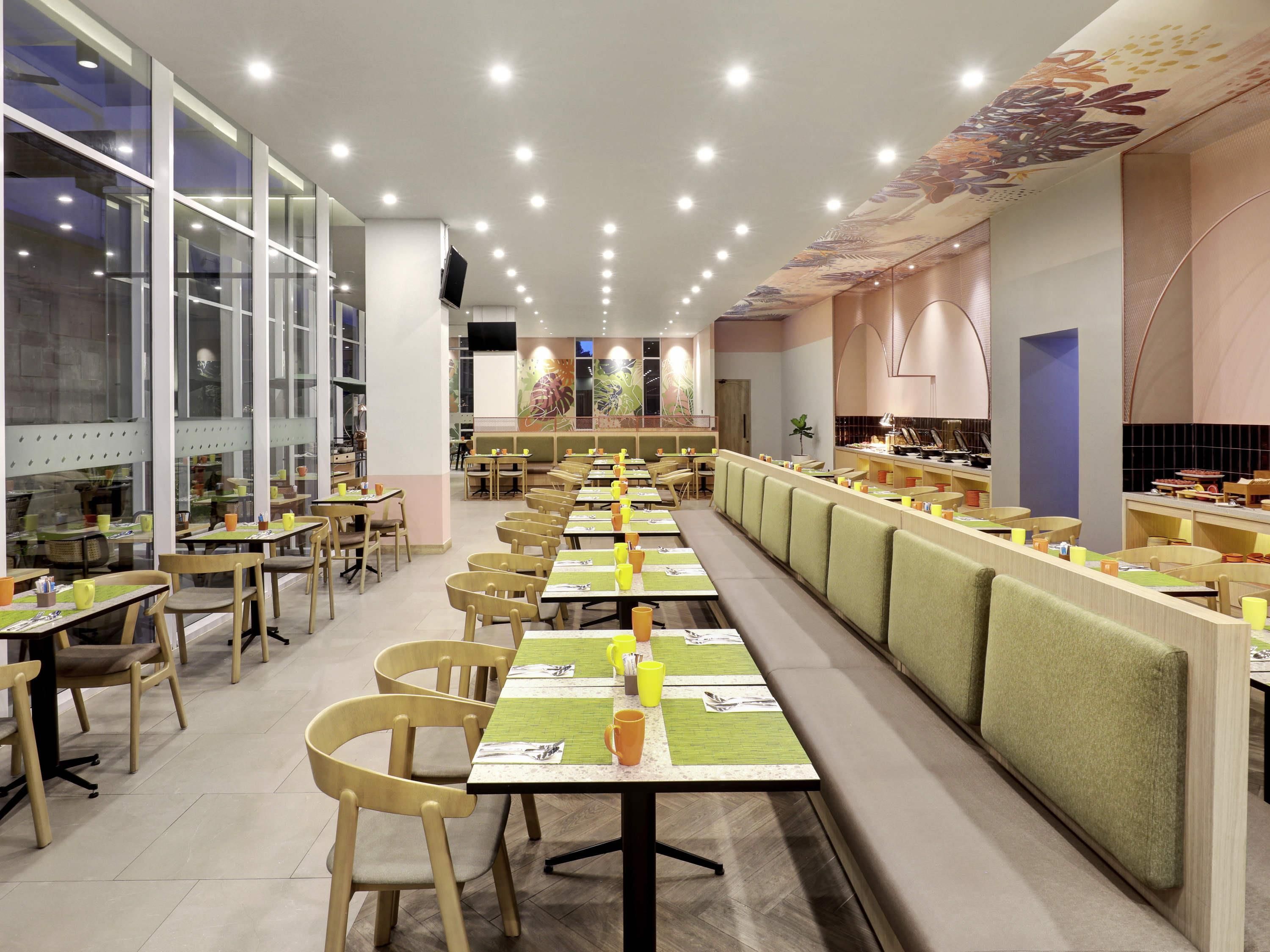 Un restaurant doté de plusieurs tables et chaises, d’un comptoir où sont exposés des plats, et d’un plafond orné de motifs floraux.