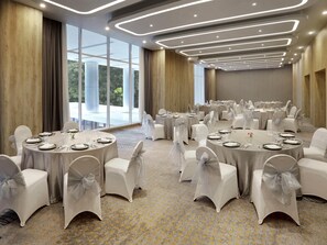A conference room with round tables, white chairs, and a carpeted floor. - ibis Styles Bogor Pajajaran (Bogor)
