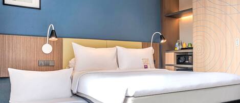 Una habitación de hotel moderna con una cama, lámparas de noche, un cuadro enmarcado en la pared y un diseño de paneles de madera en la pared.