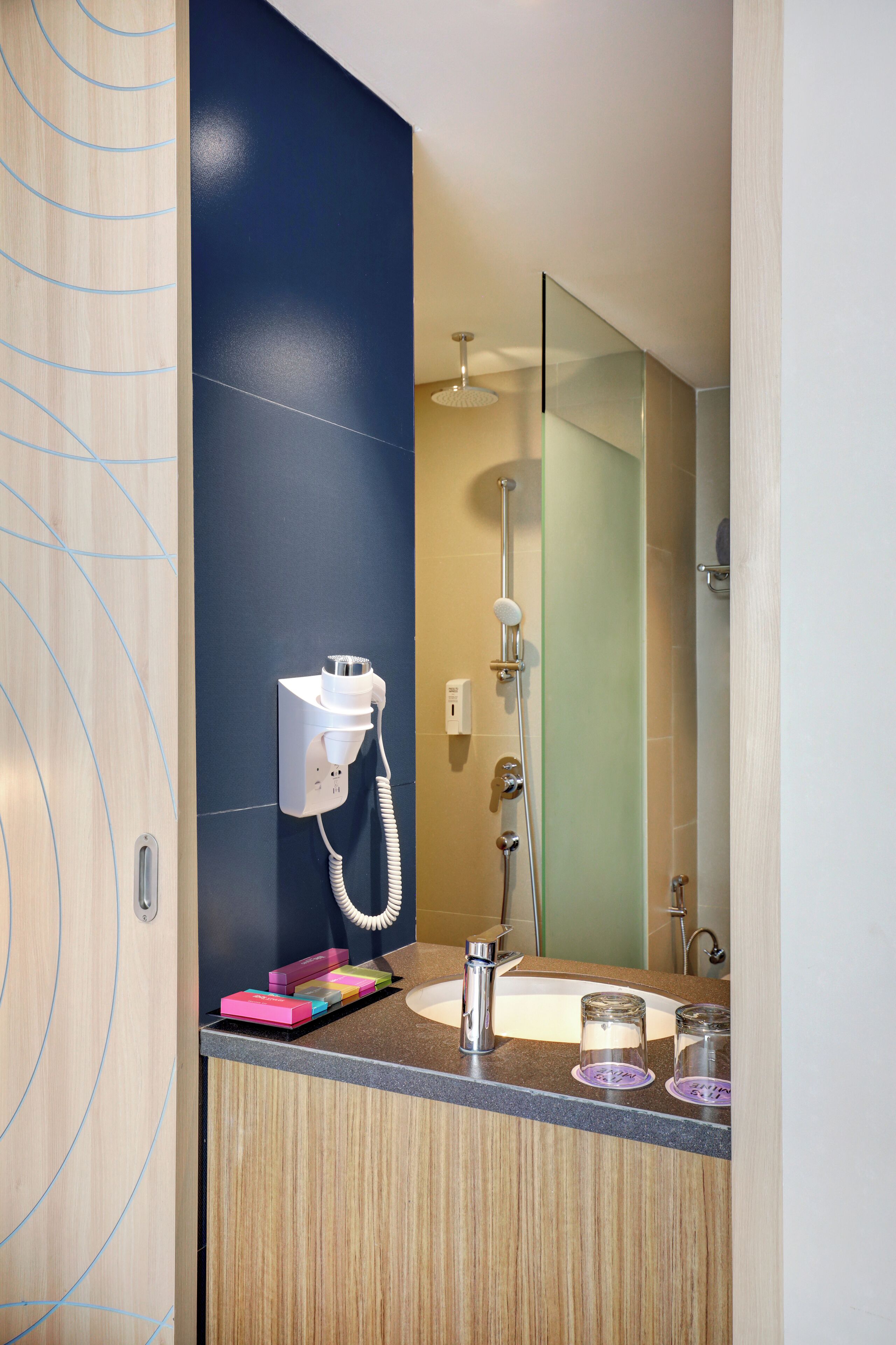 A modern bathroom with a built-in hairdryer, a mirror, and a shower.