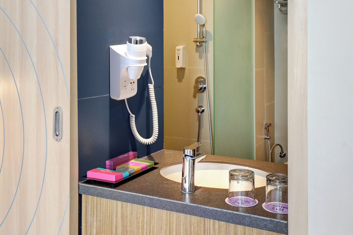 A modern bathroom with a built-in hairdryer, a mirror, and a shower.