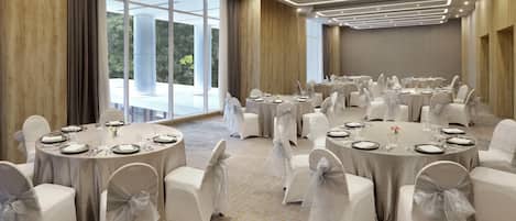 A conference room with round tables, white chairs, and a carpeted floor.