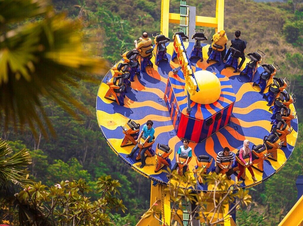 Un paseo circular de atracciones con asientos dispuestos alrededor del perímetro, frente a un paisaje verde y exuberante.